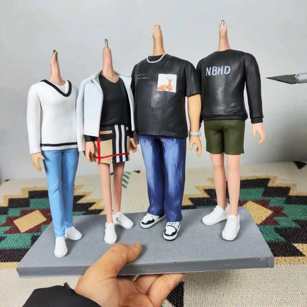 Four action figures wearing different outfits on a gray platform with a colorful rug in the background.