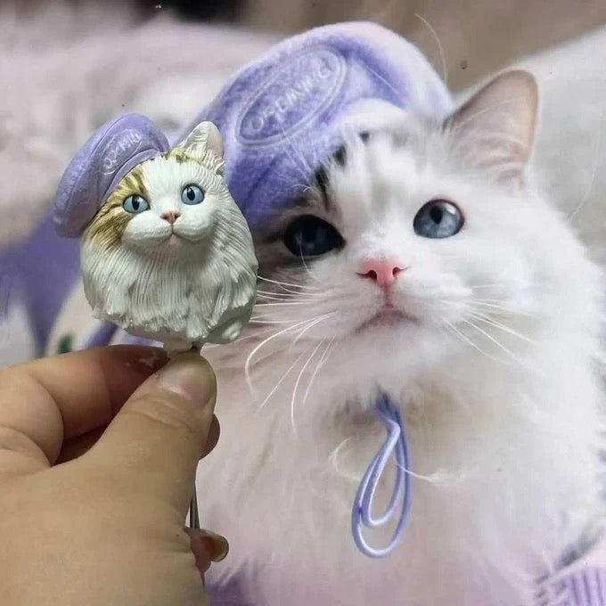 White cat with blue eyes wearing a purple towel, holding a small figurine of itself.